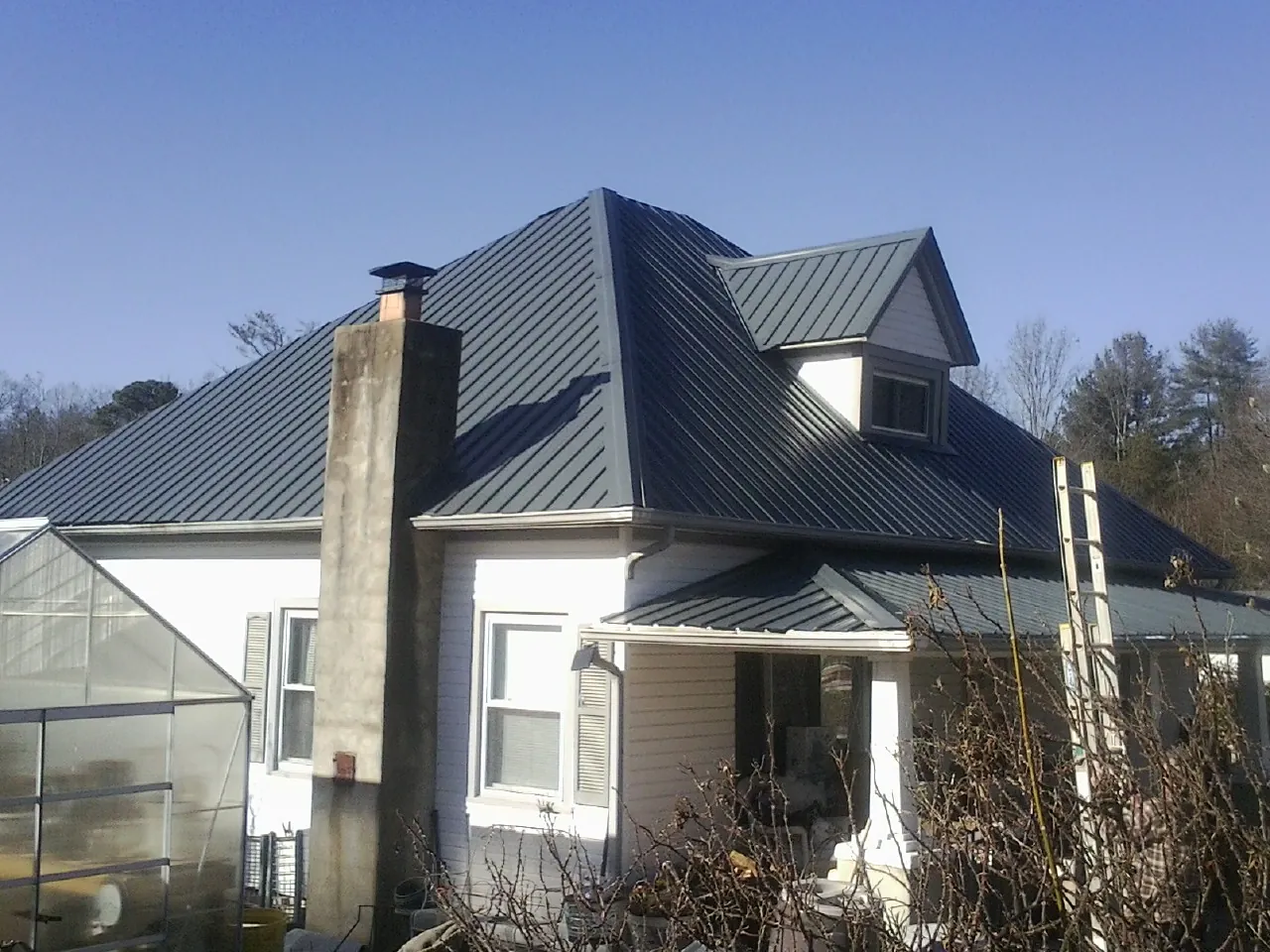 Dark blue standing seam metal roof on a white farmhouse with dormer — Slate & Tile Roof Repair by Roofing Brothers in Robbins